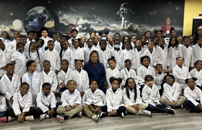  third grade students with white coats on with Ms. Chambers in the middle